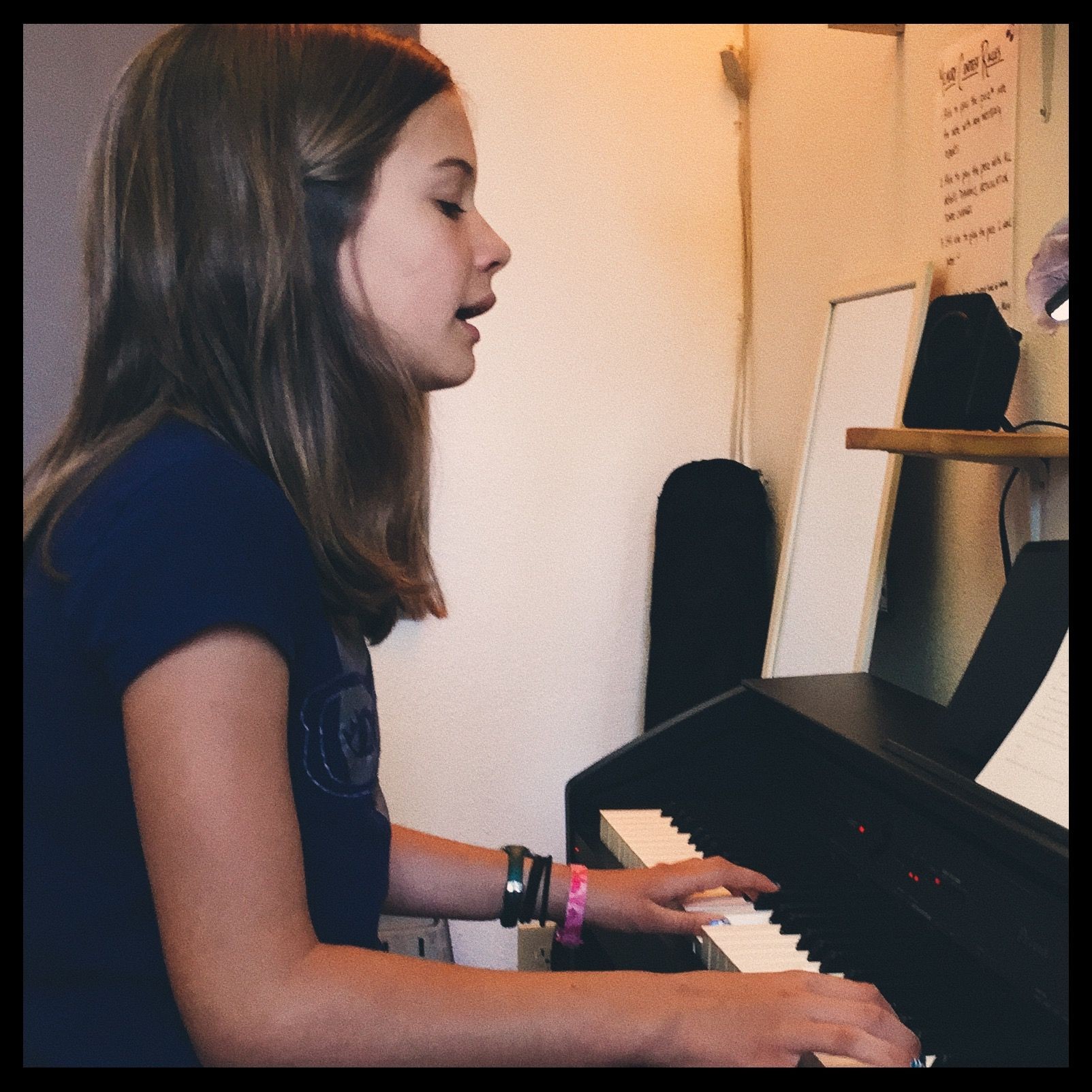 elementary school aged child with mid length hair singing while playing the piano during her piano and voice lesson