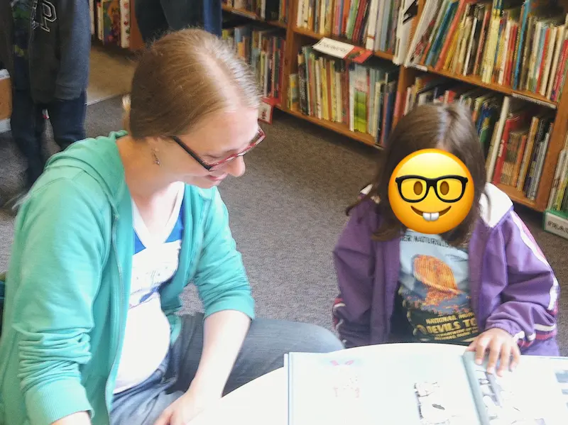 Sarah helping a young student read during a library visit