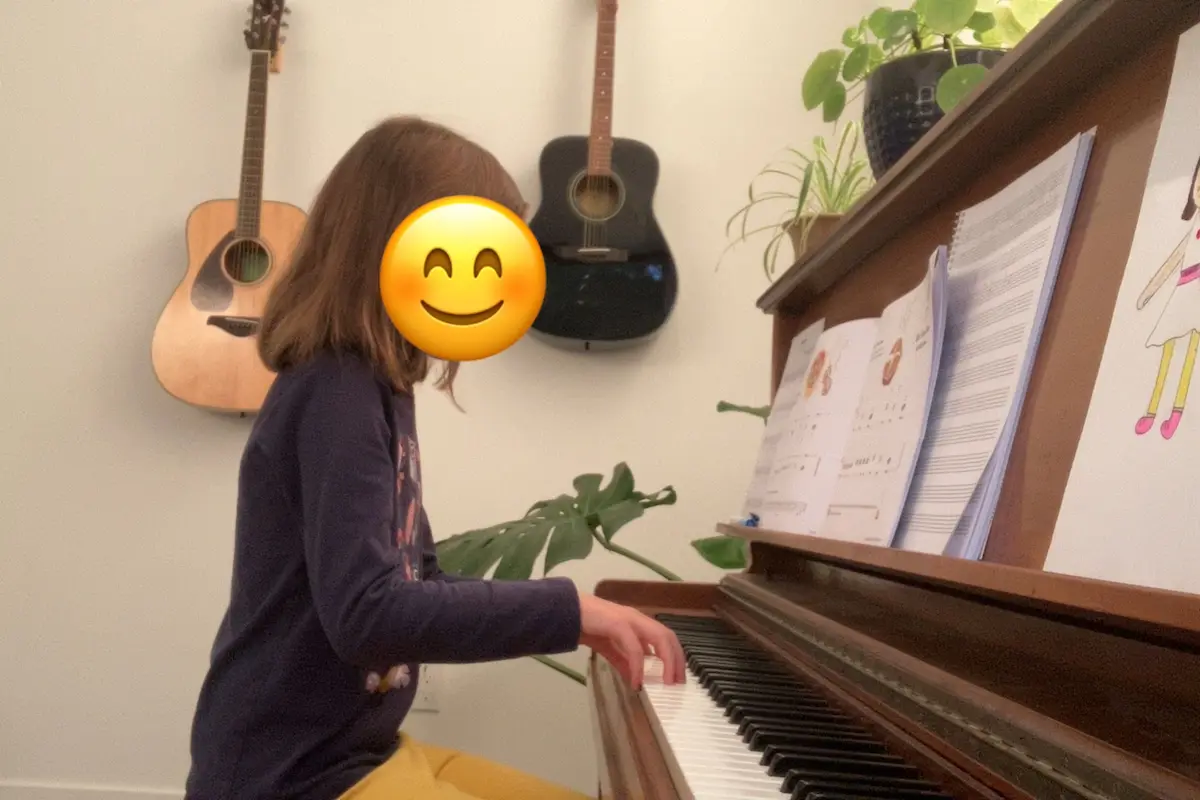 A young girl plays piano with round hands and guitars behind her